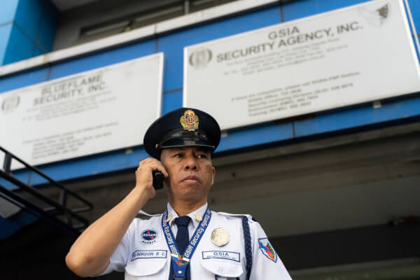 Security officer assisting clients via communication device for administrative security services in the Philippines – Gervasio Group of Companies